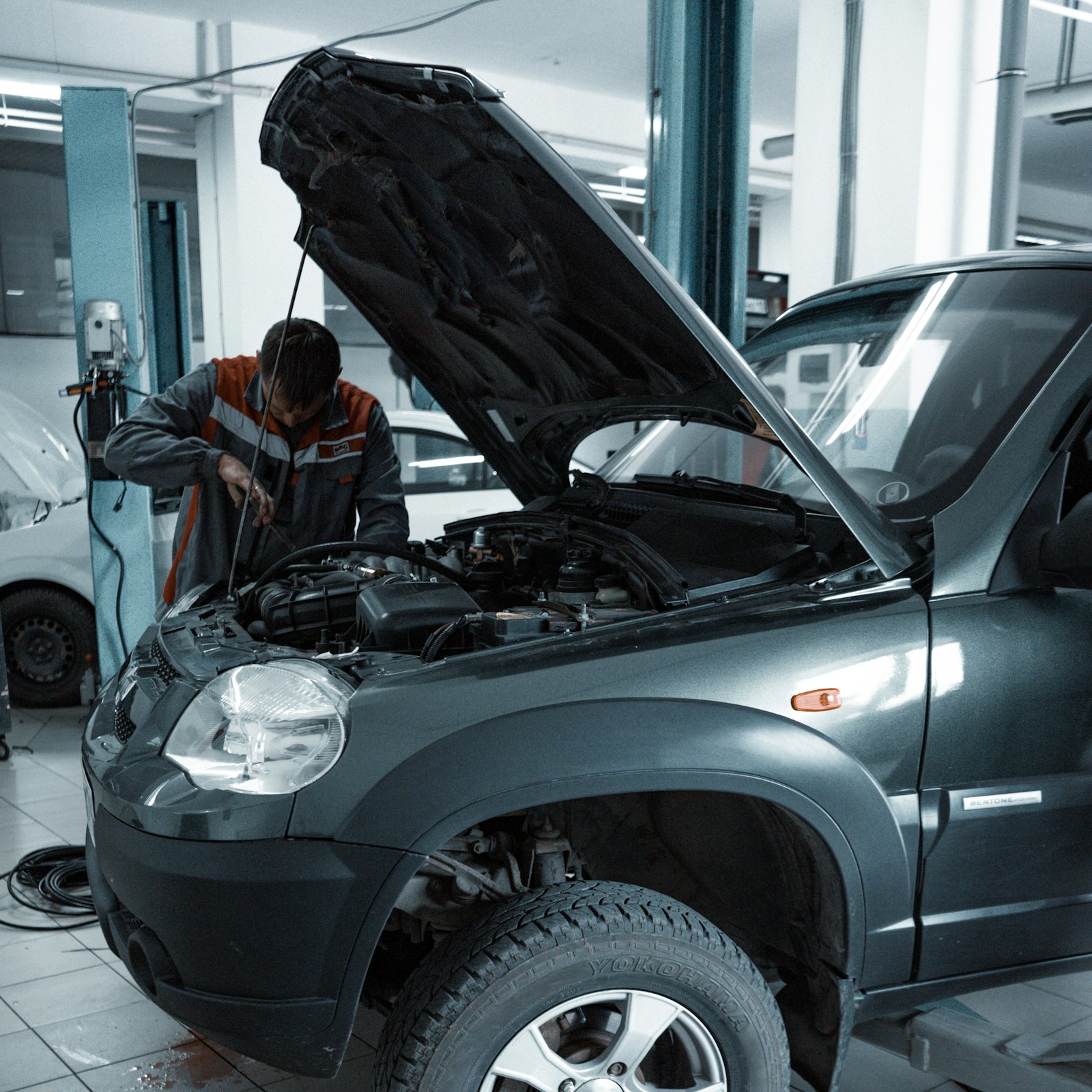 Mechanic working under the open hood of an SUV in the workshop